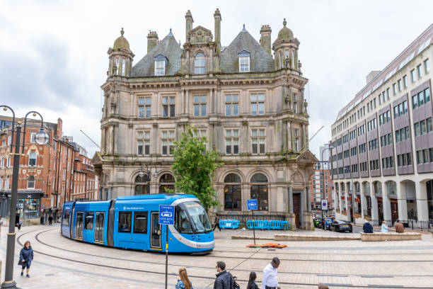 Contemporary tram running in Odense Denmark along modern residential buildings on bright summer day with blue sky