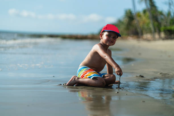 Latino boy from Cartagena Colombia, between 4 and 5 years old;  walking alone on the beach during a beautiful morning