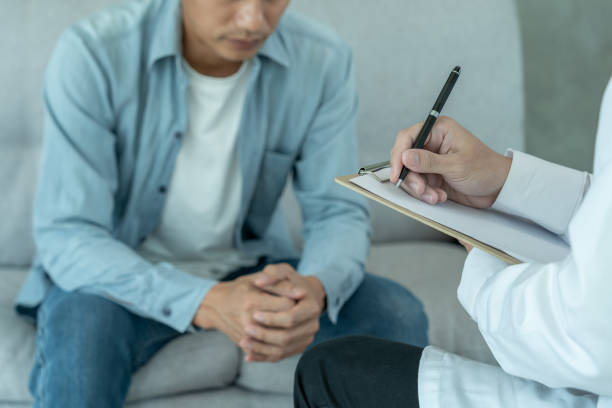man with mental health problems is consulting. psychiatrist is recording the patient's condition for treatment. encouragement, love and family problem, bipolar , depression patient, protect suicide - うつ病 ストックフォトと画像