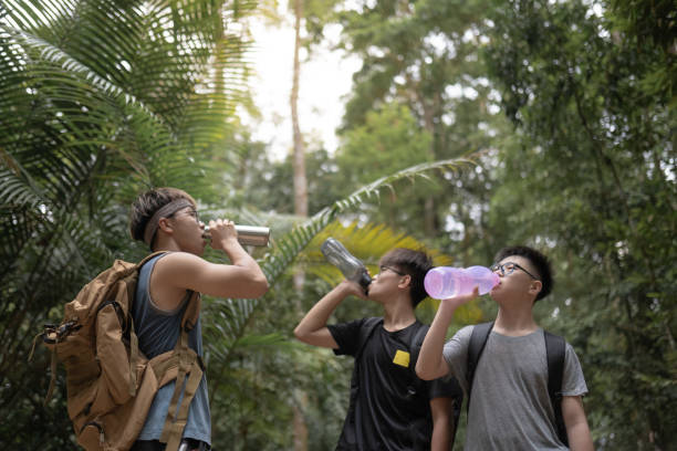 istock Chinese teenagers with a backpack drinking water while hiking in forest. 2164370073