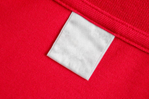 istock Blank white laundry care clothes label on red shirt fabric texture background 2164371073