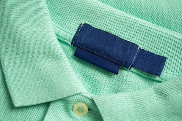 istock Blank blue laundry care clothes label on green shirt fabric texture background 2164371078