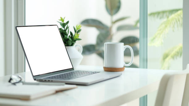 istock Mockup laptop with empty display, coffee cup, books white table. 2164371638