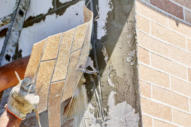 Installing brick veneer outside, construction worker decorates facade of house with exterior panel of fake thin brick.