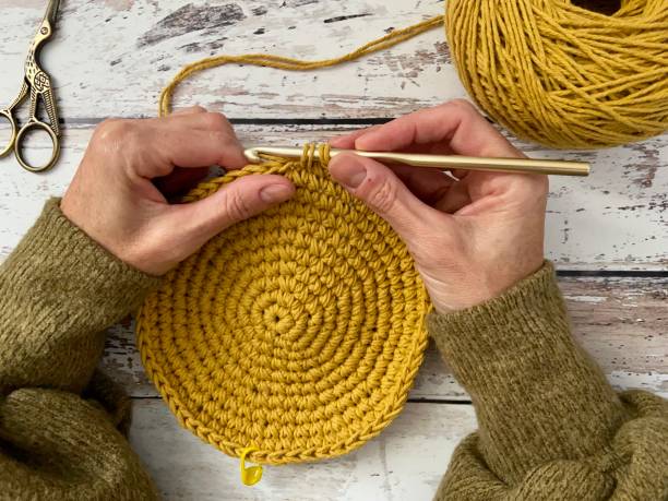 Female hands crocheting on a wooden surface. High quality 4k footage
