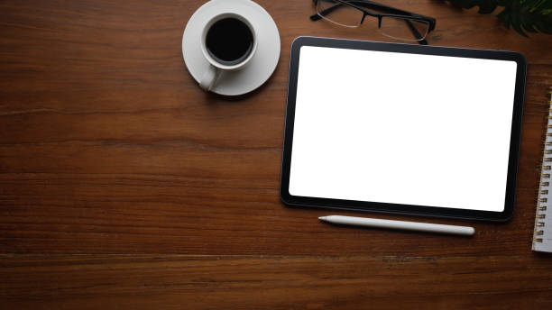 istock Flat lay, top view of digital tablet with blank display, notebook and coffee cup on wooden table. 2164377499