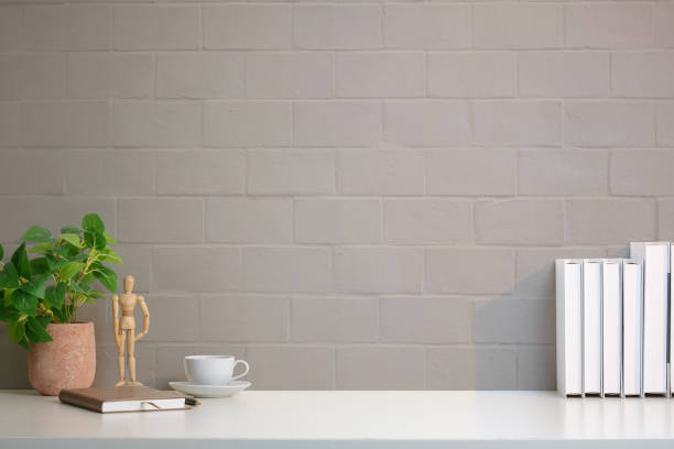 istock A simple and modern workspace setup featuring a clean white desk against a light gray brick wall background. 2164380833