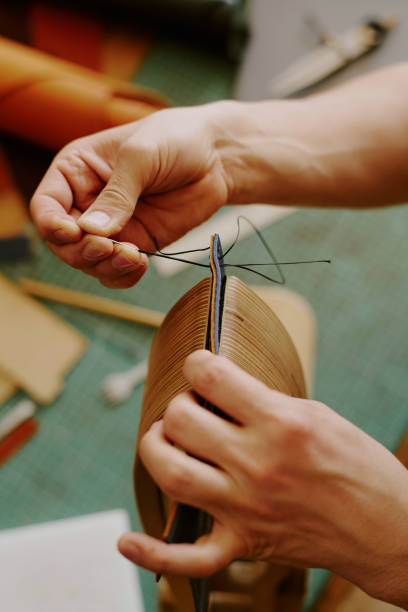 Unrecognizable male hands sewing stitches painstakingly to create leather card holder