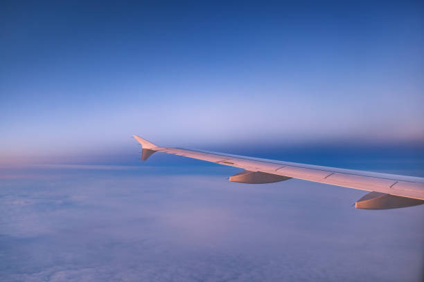 istock Airplane flying over color sky clouds during scenic sunset or sunrise cloudscape, view from plane window of wing turbines and horizon 2164389027
