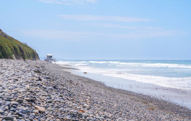 Rocky beach with lifeguard post and surfers in the distance at Encinitas, California