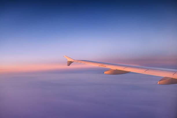 istock Airplane flying over color sky clouds during scenic sunset or sunrise cloudscape, view from plane window of wing turbines and horizon 2164389121