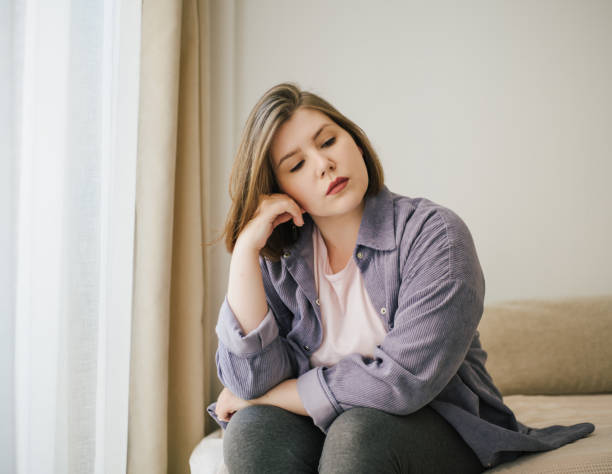 istock Thoughtful plus-size woman resting head on hand, in deep contemplation. Calm indoor setting, self-reflection, and peaceful atmosphere. Casual home attire 2164392143