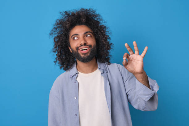 istock Joyful Young Man Expressing Approval Against Vibrant Blue Background 2164392679