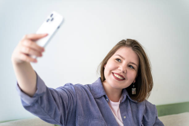 istock Plus-size woman taking selfie with smartphone, smiling. Body positivity, modern technology use, and social media interaction 2164392994