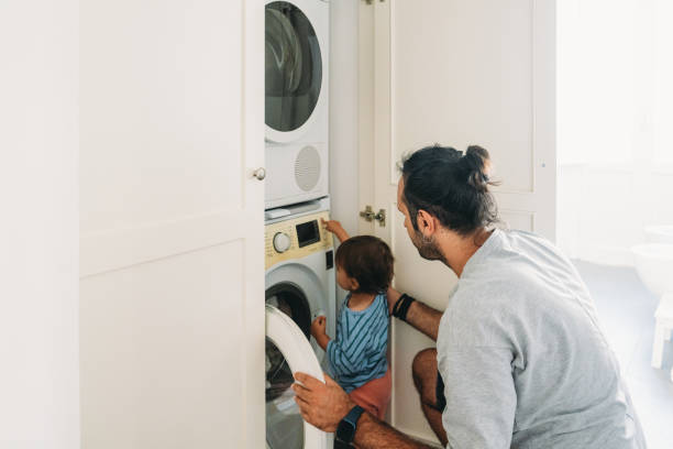 istock Father and son doing laundry together in a modern home 2164393510