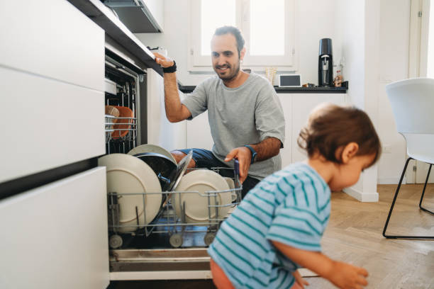 istock Father emptying dishwasher while toddler plays in kitchen 2164393511