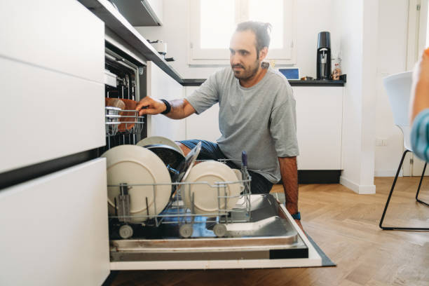 istock Man is putting the dishes in the dishwasher in a modern kitchen 2164393514