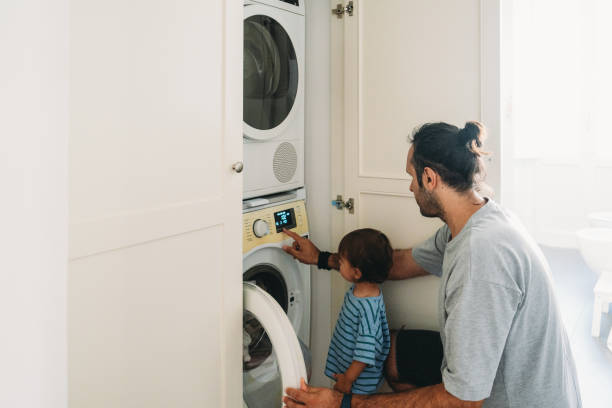 istock Father teaching son how to use washing machine at home 2164393516