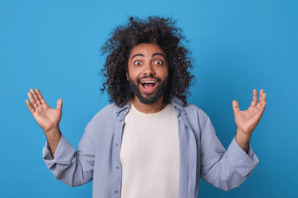istock Joyful Man Celebrates With Open Arms Against Vibrant Blue Background 2164394667