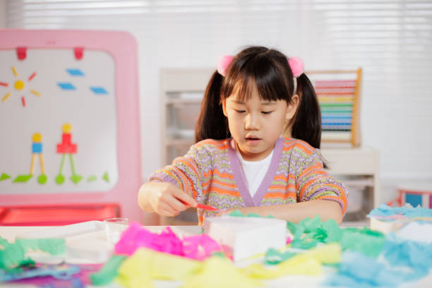 A medium shot of a young girl engaged in crafting at home