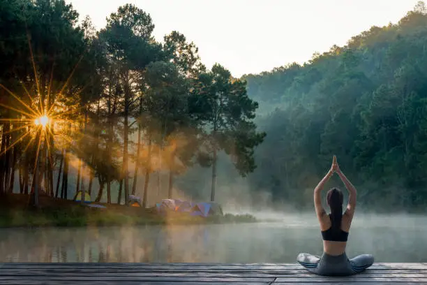 Young Woman Practicing Yoga In The Nature.female Happiness. Landscape Background Young Woman Practicing Yoga In The Nature.female Happiness. Landscape Background