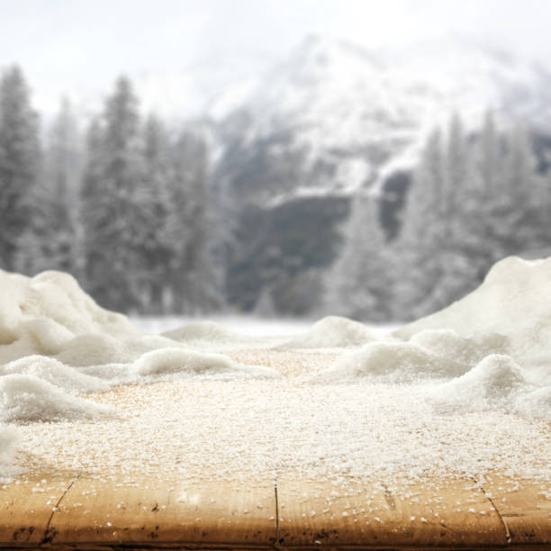 istock Empty wooden table with snow and copy space.  Blurred snowed covered trees and mountains background. 2164401764