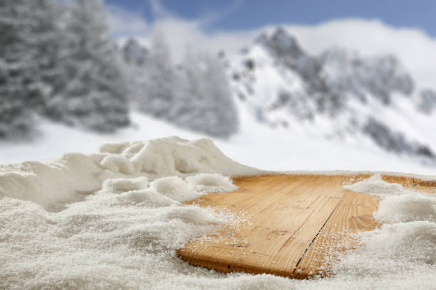 istock Empty wooden table with snow and copy space.  Blurred snowed covered trees and mountains background. 2164402289