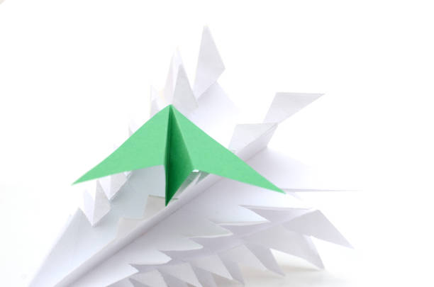 A close-up of a hand holding an orange paper airplane against a blurred background, symbolizing creativity, childlike wonder, and aspirations.