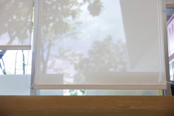 A white curtain with a mesh screen is hanging in front of a window