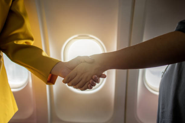 istock Pilot and stewardess shaking hands on airfield background. 2164418781
