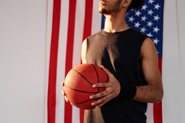 istock Basketball Player Holding Ball Standing with American Flag 2164421110
