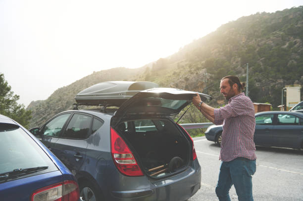 istock Man loading car trunk outdoors on a road trip during daylight in the mountains 2164421301