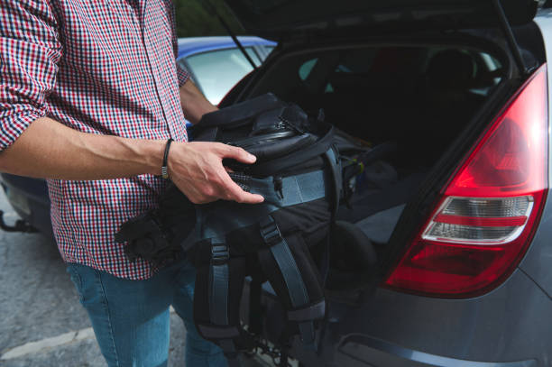 istock Man loading backpack into car trunk for a road trip or adventure 2164421315