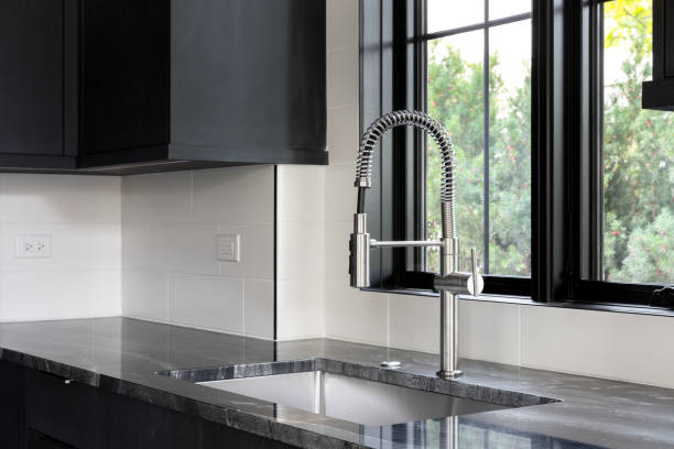istock A kitchen faucet detail in a kitchen with black cabinets and tiled backsplash. 2164424069