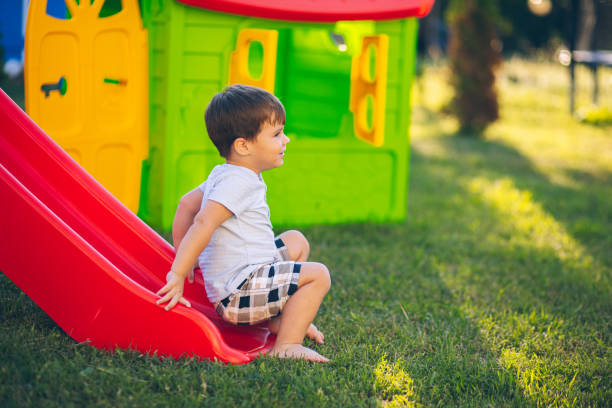 istock Little boy climbing up a slide in her backyard playground 2164427861