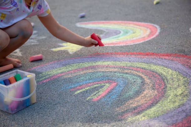 istock Kids draw a rainbow on the asphalt with colored chalk. Sidewalk. 2164442583