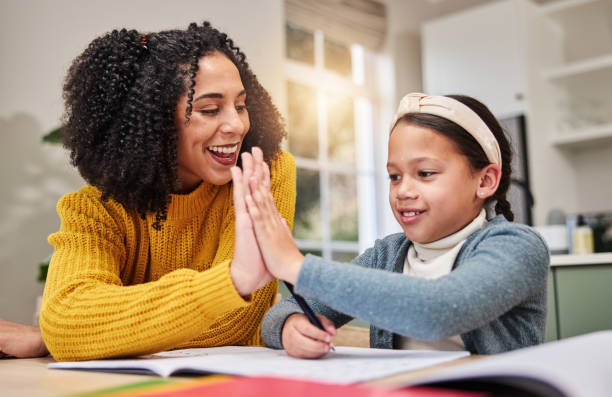 istock Mom, smile and high five with girl for homework, correct answer and learning math in home. Mama, daughter and excited with palm connection for education, celebration and success for teaching equation 2164448809