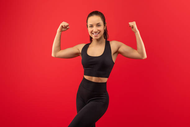istock Smiling Young Woman Flexing Muscles in Black Active Wear 2164472616