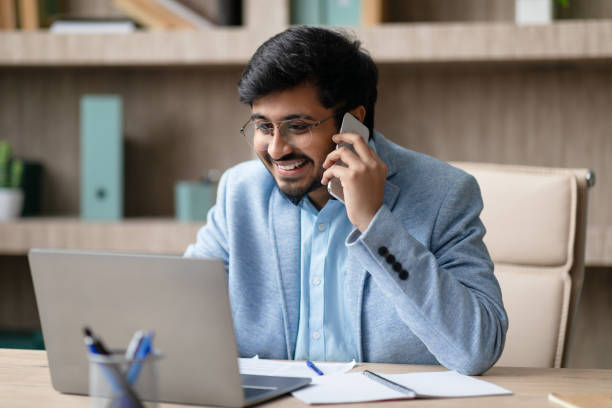 istock Middle Eastern businessman communicating by phone using laptop at office 2164473851