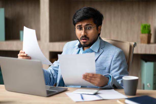 istock Unhappy Hindu businessman managing paperwork issues in office setting 2164473938