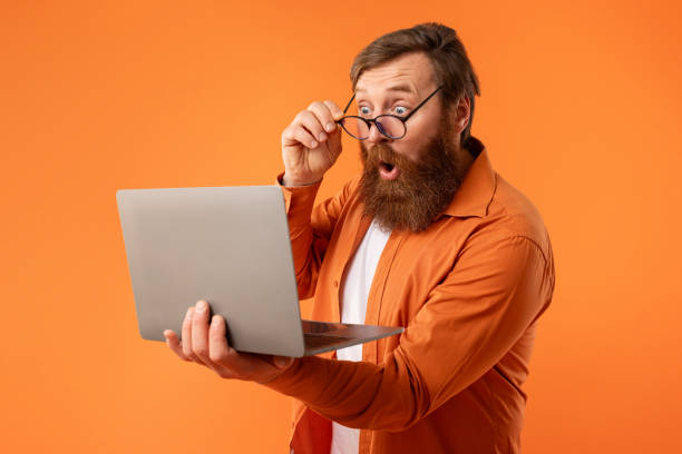istock freelancer guy with beard looking at laptop touching glasses, studio 2164475891