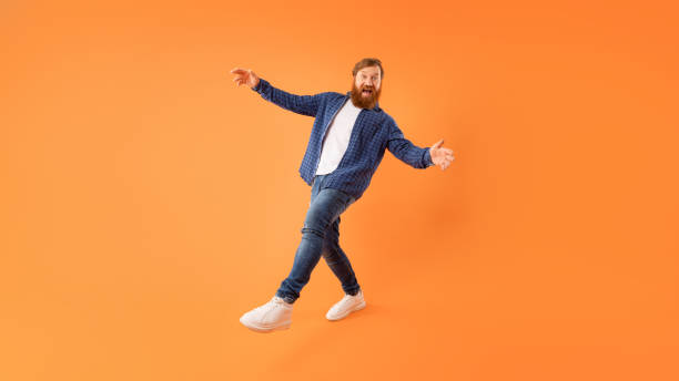 Positive redhaired guy with beard fooling posing on orange background
