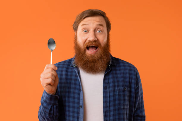 istock Emotional man with red hair and beard holding spoon, studio 2164475986