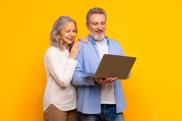 istock Modern European mature couple browsing website together on laptop, studio 2164478037