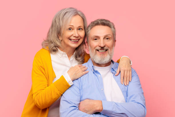 istock Joyful elderly couple radiating happiness and love hugging, pink studio 2164478084