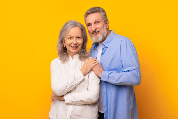 istock Affectionate happy senior couple embracing tenderly against yellow studio backdrop 2164478106