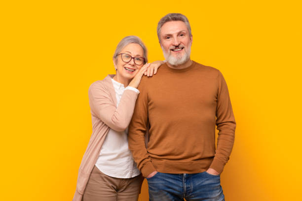 istock Happy Caucasian elderly couple embraces against yellow studio backdrop 2164478111