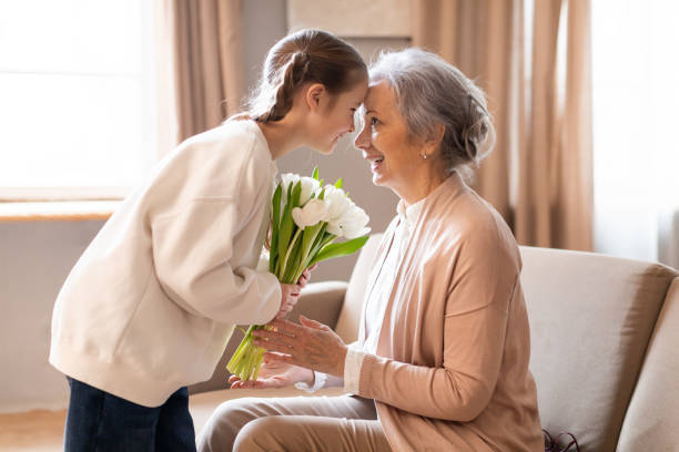 istock Young Woman Surprising Elderly Lady With a Bouquet 2164481034