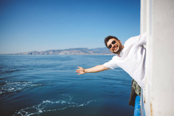 Small white motor boat with one adult man on board runs fast in the blue Mediterranean sea on a sunny summer day, back view. Gulf of La Spezia, Liguria, Italy, southern Europe.