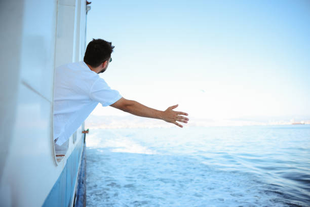 Young tourist man moving around Turkey, using a ferry boat. He is wearing sunglasses, watching the Izmir panorama around her.